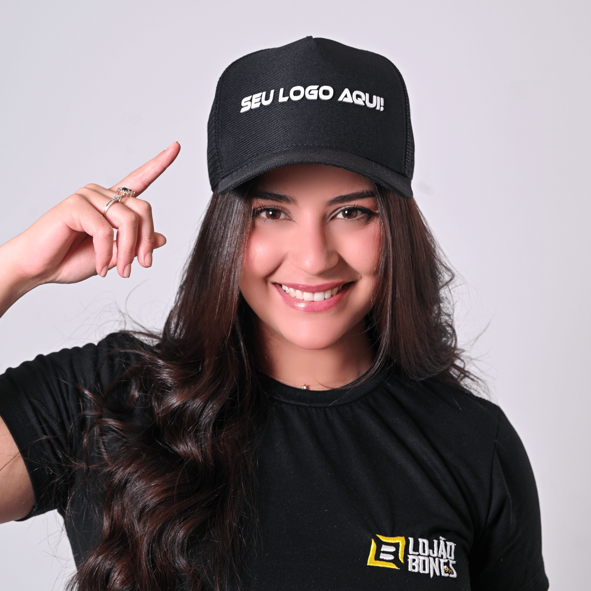 Modelo feminina sorrindo usando boné preto com bordado frontal em branco.