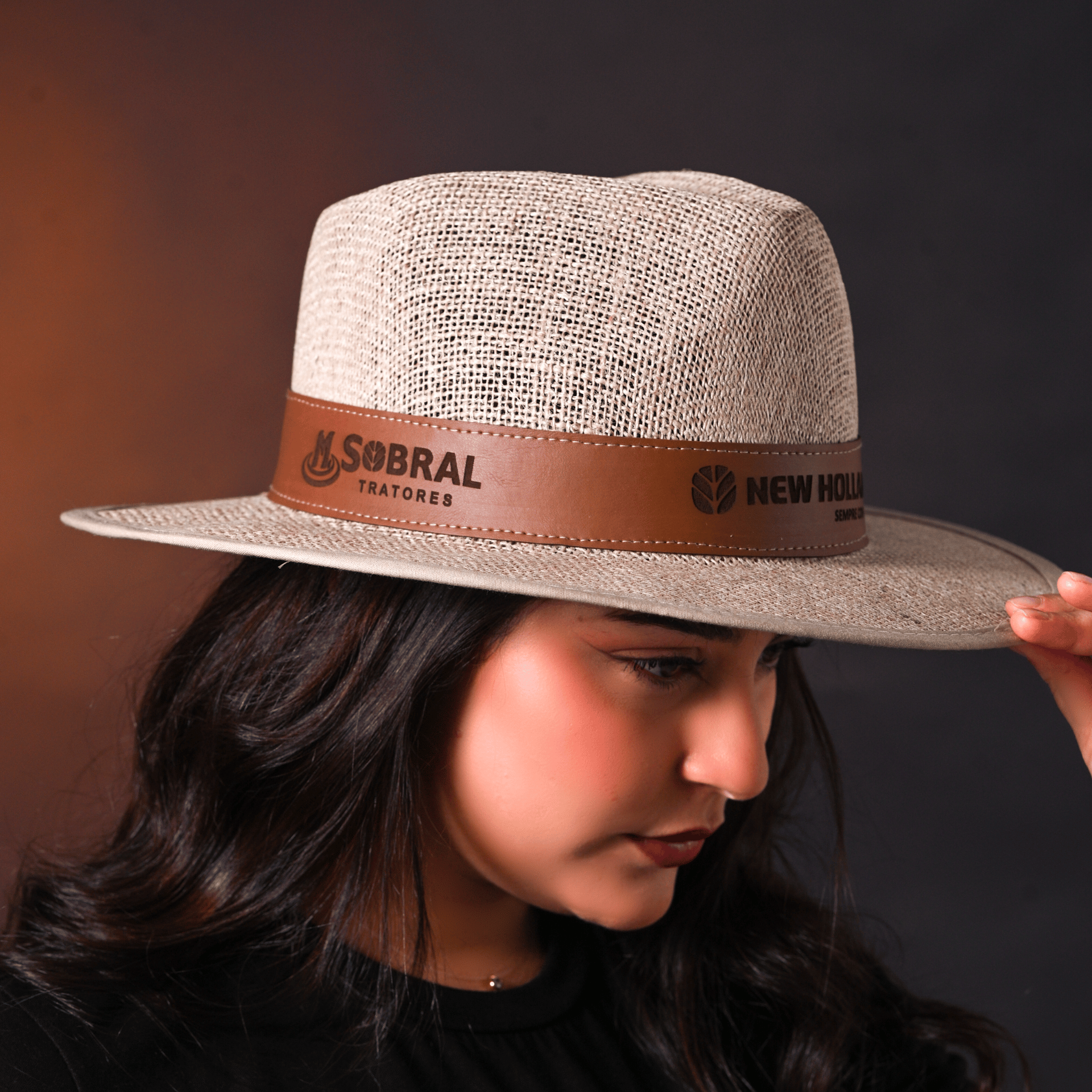 Modelo usando chapéu de palha cor clara com faixa escura com logo.