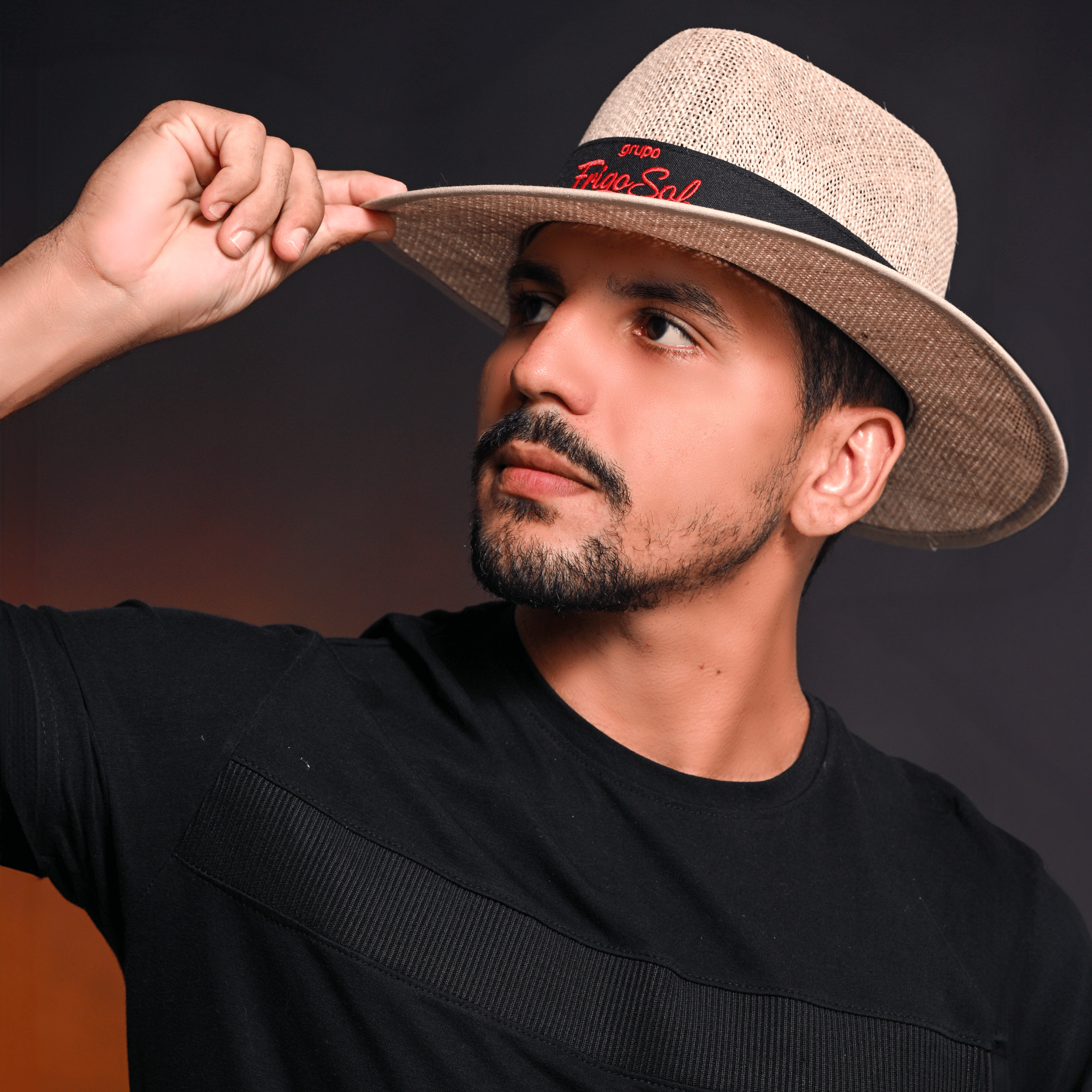 Homem ajustando chapéu de palha de aba média na cabeça, olhando para a lateral.