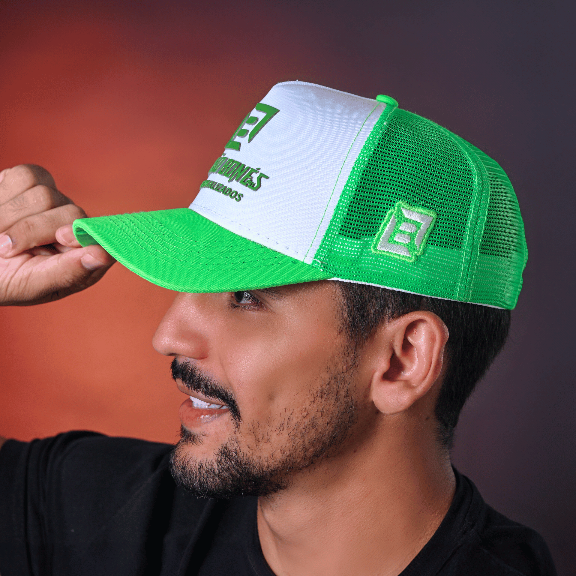 Homem sorrindo usando boné trucker verde com tela branca e aba curva.