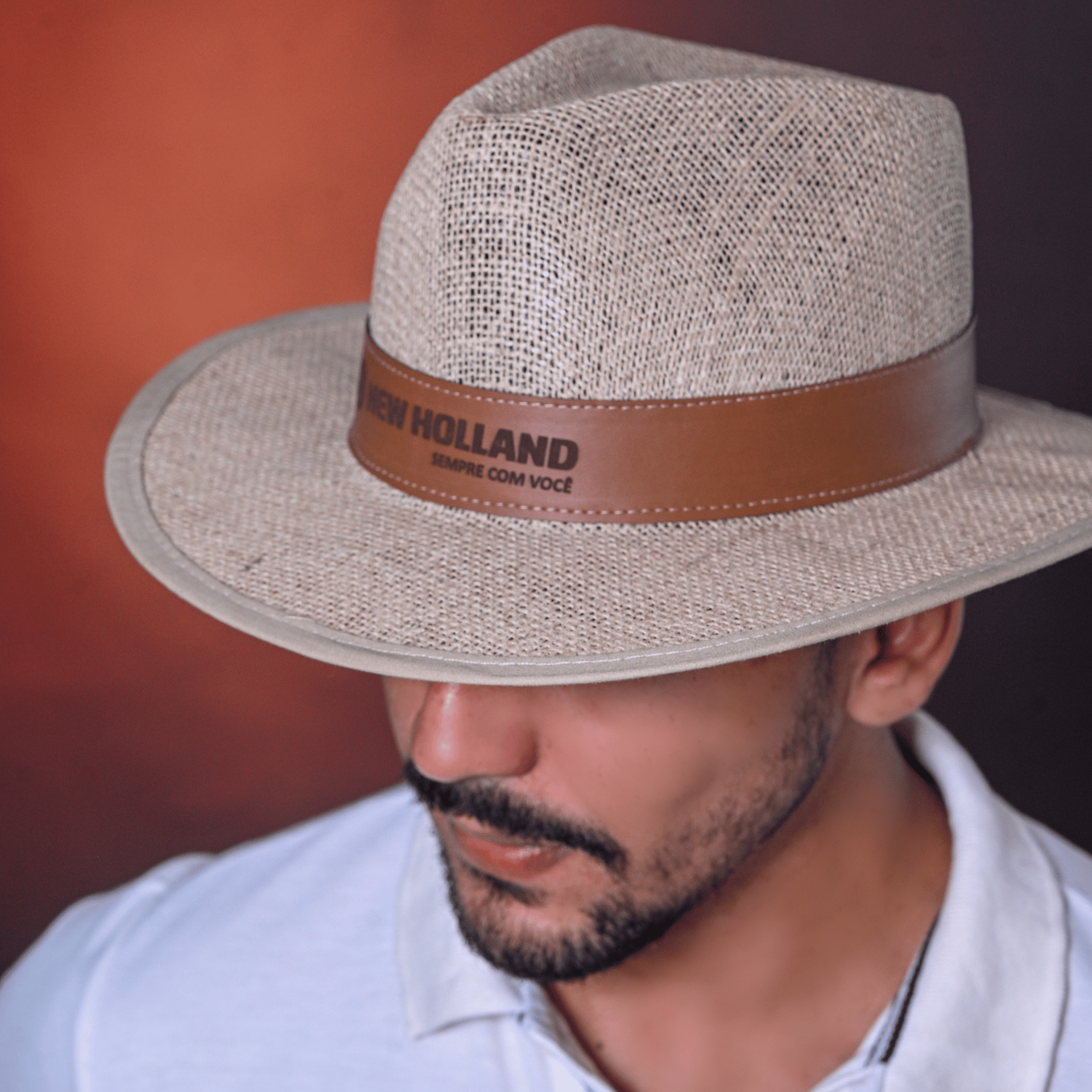 Homem usando chapéu de feltro cor clara com faixa de couro caramelo.