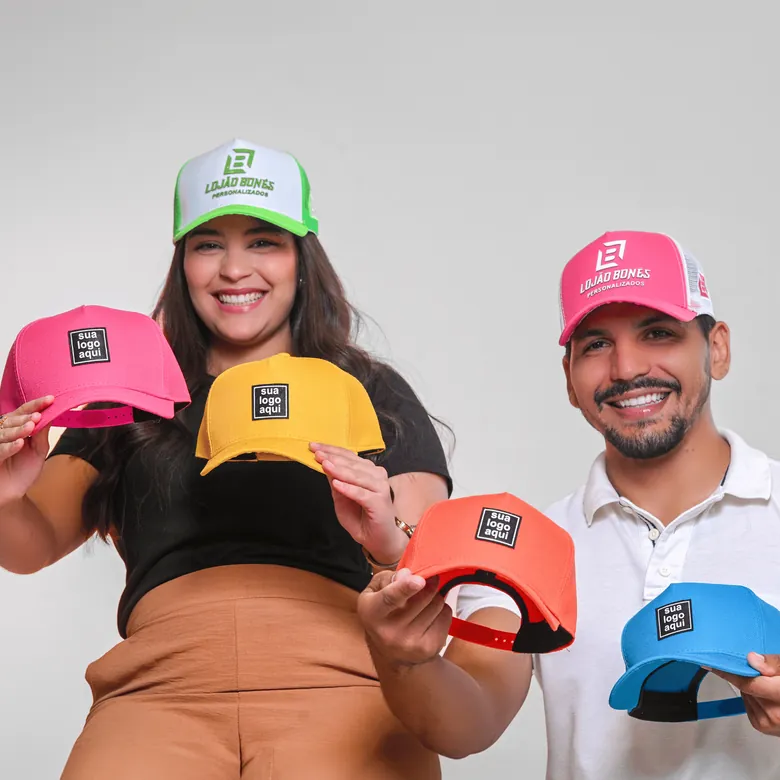 Casal sorrindo com bonés personalizados em cores variadas