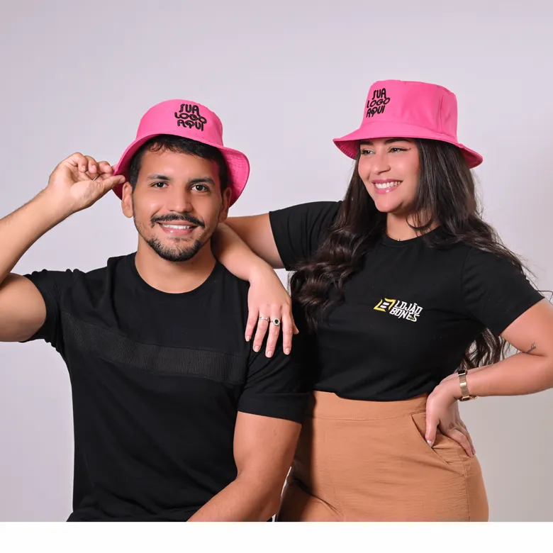 Casal usando bucket hats rosa personalizados com "sua logo aqui" e logo do Lojão dos Bonés